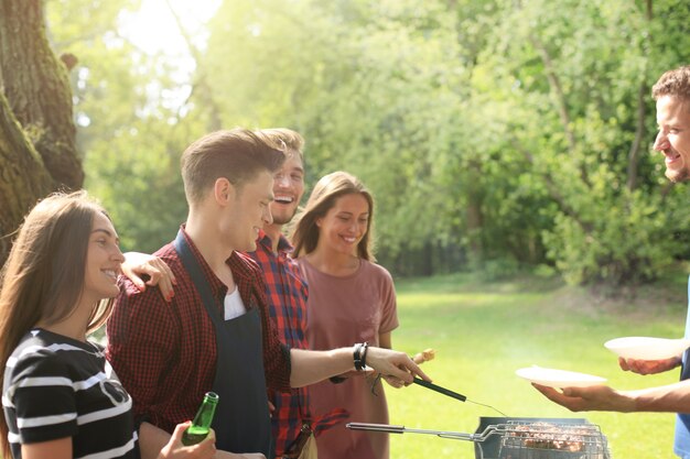 Amigos felices asando carne y disfrutando de una fiesta de barbacoa al aire libre.