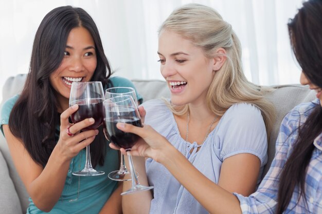 Amigos felices brindando con vino tinto juntos