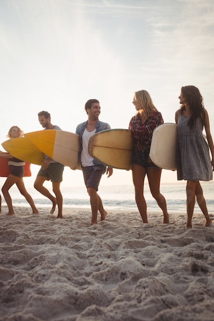 Amigos felices caminando con tablas de surf