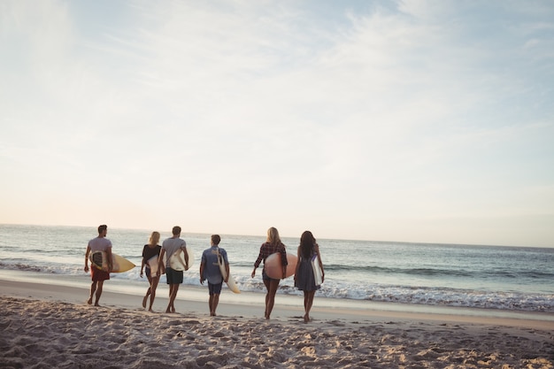 Amigos felices caminando con tablas de surf