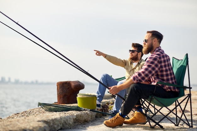 amigos felices con cañas de pescar en el muelle