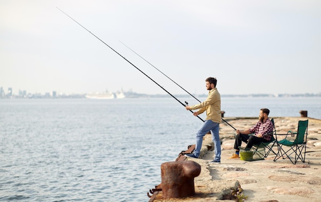 amigos felices con cañas de pescar en el muelle