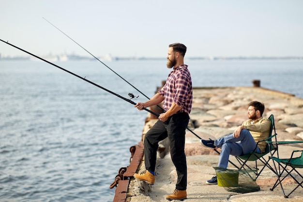 amigos felices con cañas de pescar en el muelle