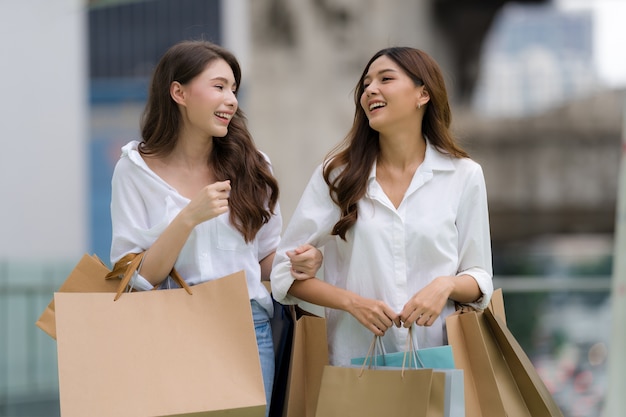 Amigos felices de compras, dos mujeres jóvenes están sosteniendo bolsas de la compra.