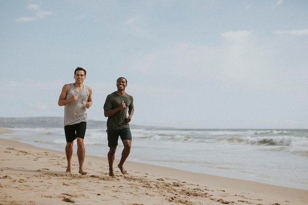 Amigos felices corriendo en la playa juntos