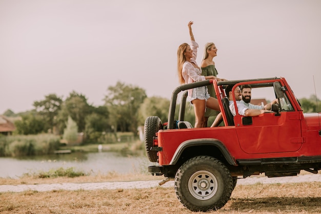 Amigos felices divirtiéndose en coche descapotable en vacaciones