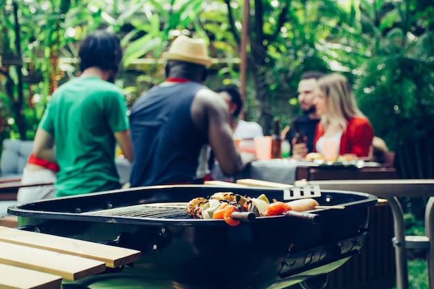 Amigos felices con fiesta de barbacoa en la naturaleza.