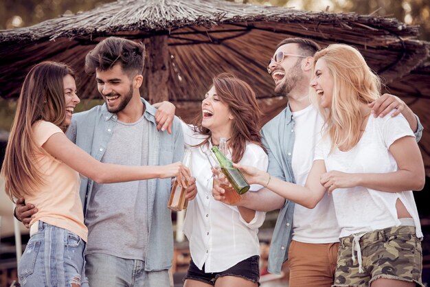 Amigos felices de fiesta en la playa con bebidas