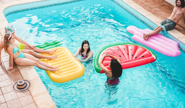 Amigos felices flotando con air lilo ball en la fiesta en la piscina - Jóvenes divirtiéndose en las vacaciones de verano