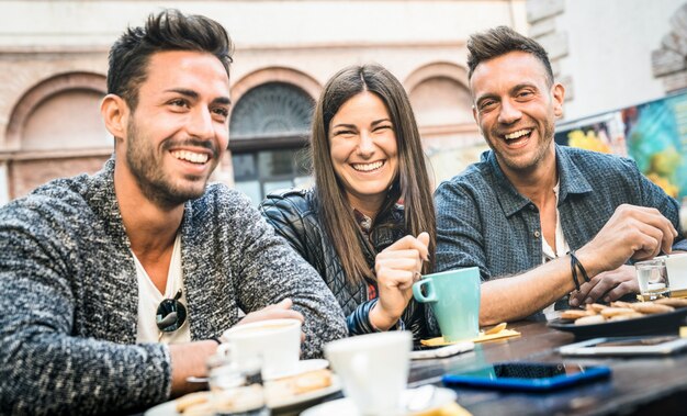 Foto amigos felices hablando y divirtiéndose en el restaurante pub bebiendo capuchino y té caliente