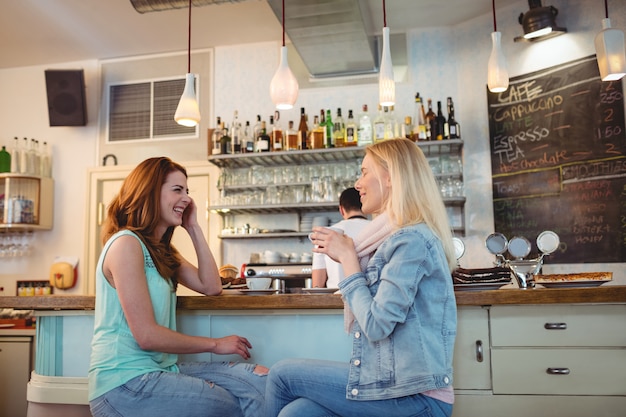 Amigos felices hablando en mostrador en cafetería