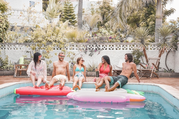 Amigos felices haciendo fiesta en la piscina - Jóvenes divirtiéndose en vacaciones de verano