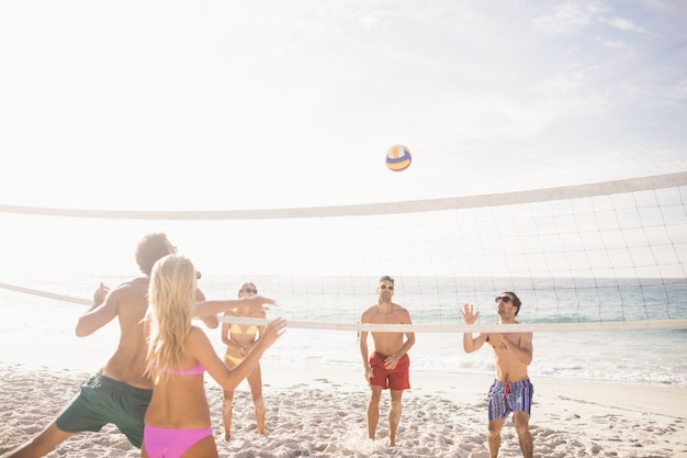 Amigos felices jugando voleibol de playa