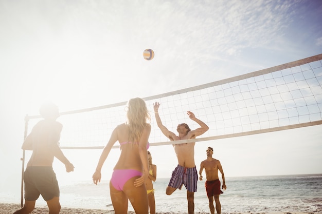 Amigos felices jugando voleibol de playa