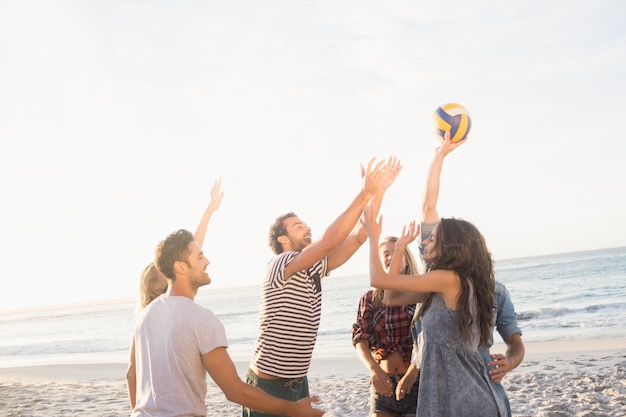 Amigos felices jugando voleibol de playa