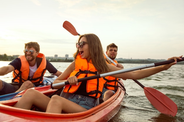 Foto amigos felices en kayak en el río con puesta de sol en el fondo