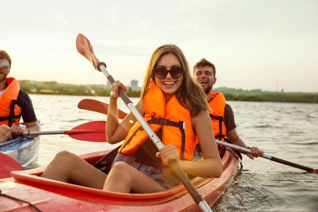 Foto amigos felices en kayak en el río con puesta de sol en el fondo