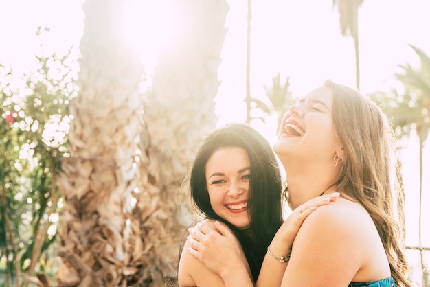 Amigos felices de las mujeres jóvenes se divierten y ríen junto con un abrazo amistoso