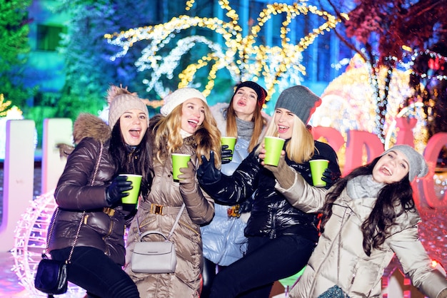 Amigos felices de las mujeres que celebran en el mercado de la Navidad