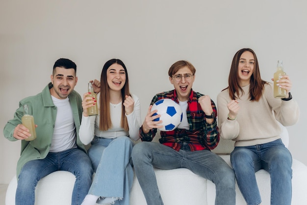 Amigos felices o fanáticos del fútbol ven fútbol en la televisión y celebran emocionalmente la victoria en casa El concepto de amistad, deportes y entretenimiento