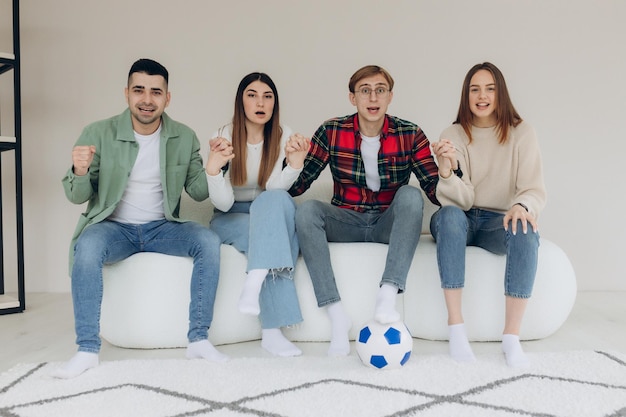 Amigos felices o fanáticos del fútbol ven fútbol en la televisión y celebran emocionalmente la victoria en casa El concepto de amistad, deportes y entretenimiento