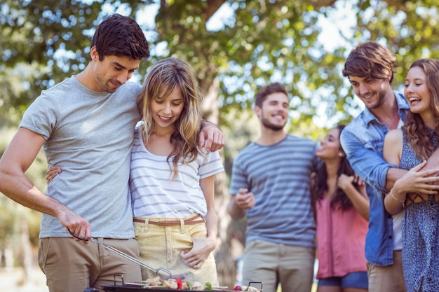 Amigos felices en el parque con barbacoa