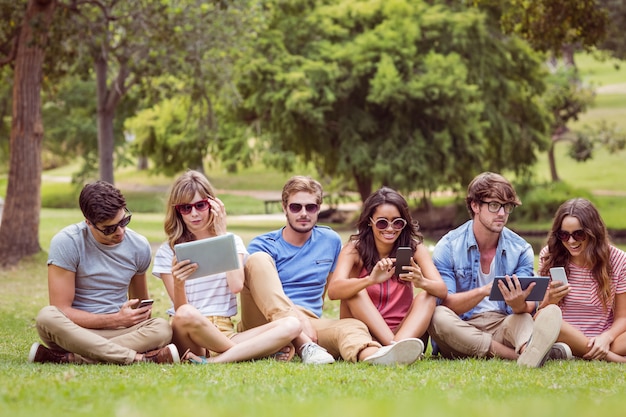 Amigos felices en el parque mirando tablet