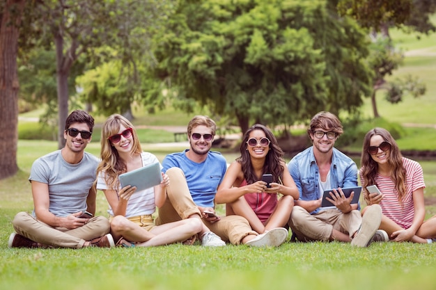 Amigos felices en el parque mirando tableta