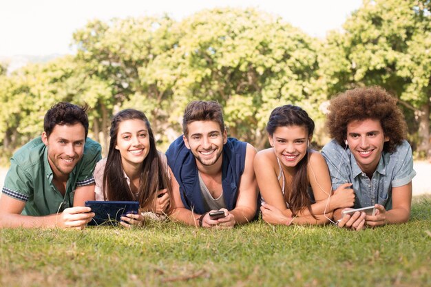 Amigos felices en el parque usando sus teléfonos