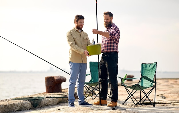 amigos felices con peces y cañas de pescar en el muelle