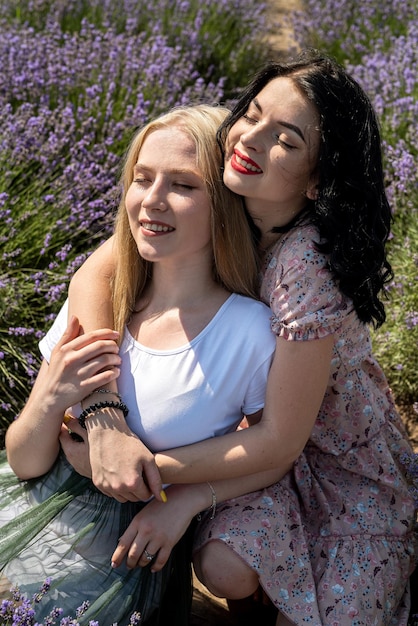 Amigos felices posando junto con flores de lavanda en un campo grande