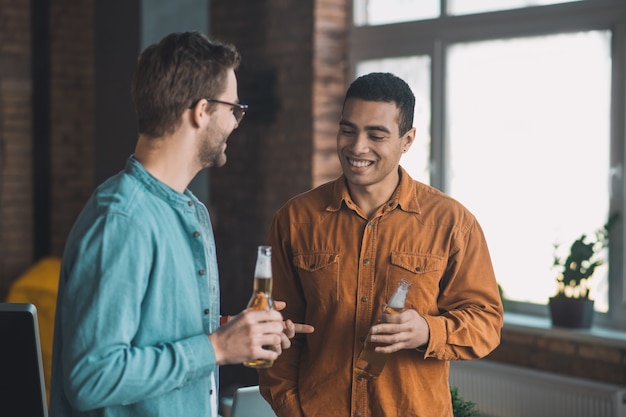 Amigos felices positivos pasar un buen rato mientras beben cervezas juntos