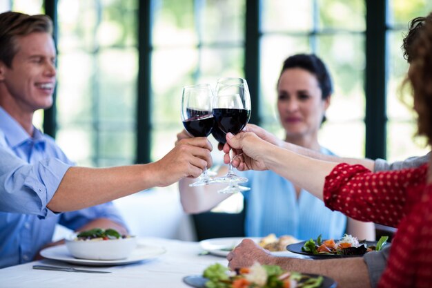 Amigos felices que tuestan una copa de vino mientras almuerzan