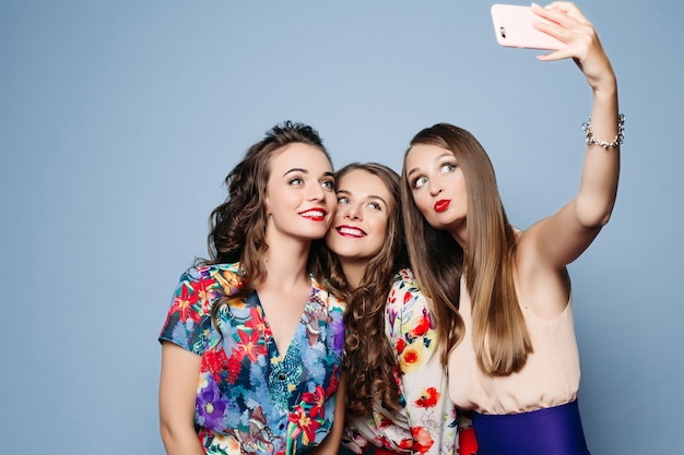Amigos felices en ropa de moda tomando selfie sobre backgrou azul