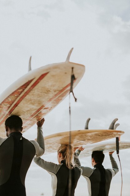 Foto amigos felices surfeando en la playa