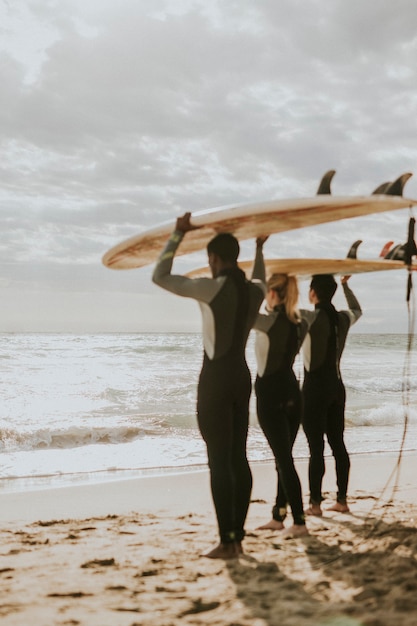 Foto amigos felices surfeando en la playa