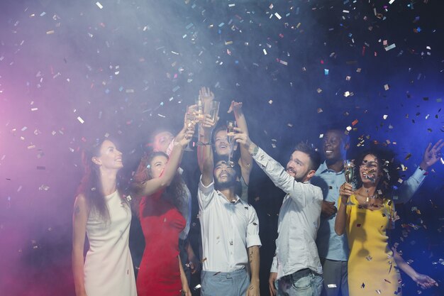 Foto amigos felices tintineando copas de champán en la fiesta de año nuevo