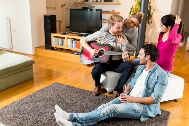 Amigos felices tocando la guitarra y escuchando música en casa