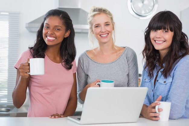 Amigos felices tomando un café junto con la computadora portátil