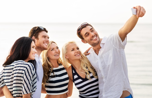 Amigos felices tomando selfies en la playa de verano
