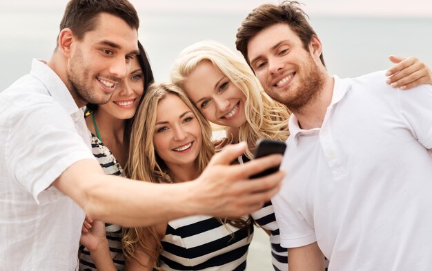 Amigos felices tomando selfies en la playa de verano