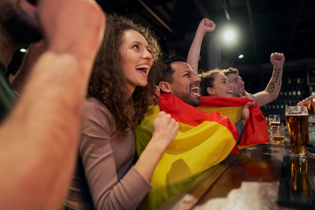 Foto amigos felices viendo un partido de fútbol en el bar.