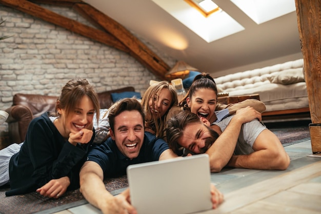 Amigos felices viendo videos divertidos en una tableta