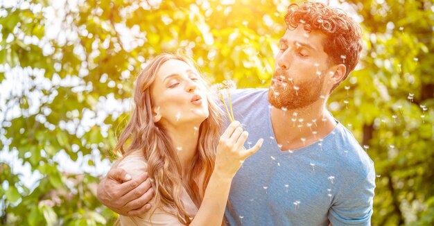 Amigos felizes a soprar dente-de-leão num parque público.