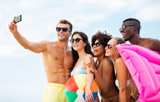 Foto amigos felizes a tirar selfie na praia de verão.