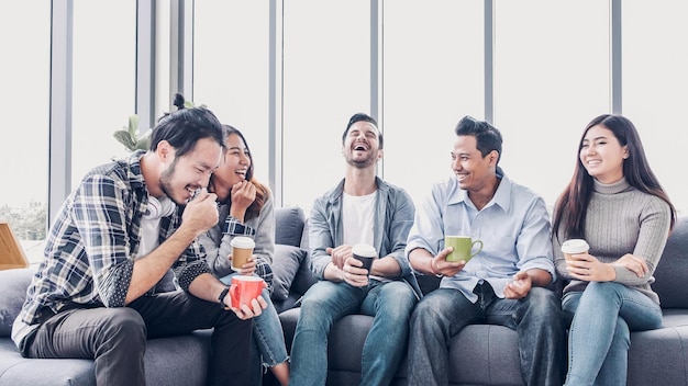 Amigos felizes a tomar café enquanto estão sentados no sofá em casa.