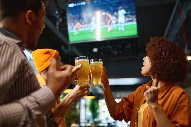 Amigos felizes bebendo cerveja e torcendo juntos no bar de esportes