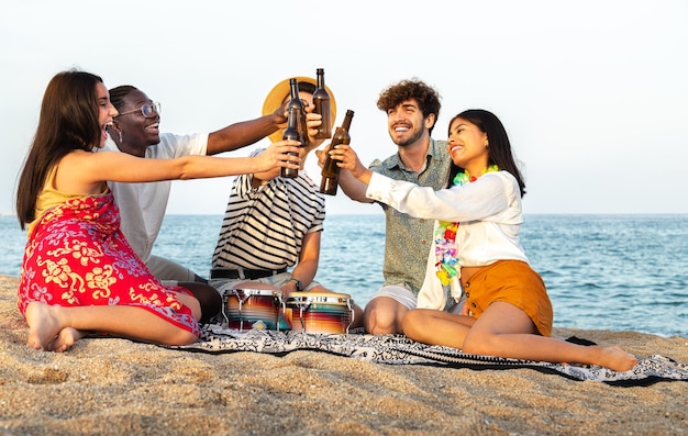 Amigos felizes brindando com cerveja juntos na praia jovens multirraciais se divertindo ao ar livre