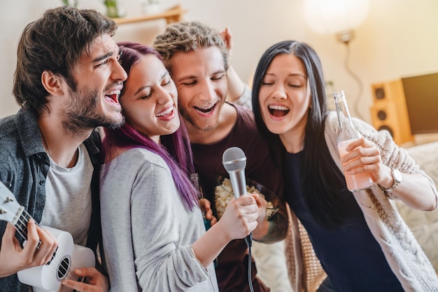 Amigos felizes cantando karaokê juntos em casa