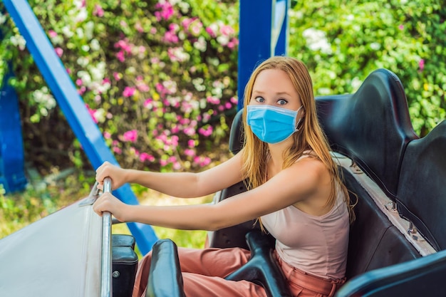 Amigos felizes com máscara médica em um parque de diversões em um dia de verão após uma epidemia de coronovírus